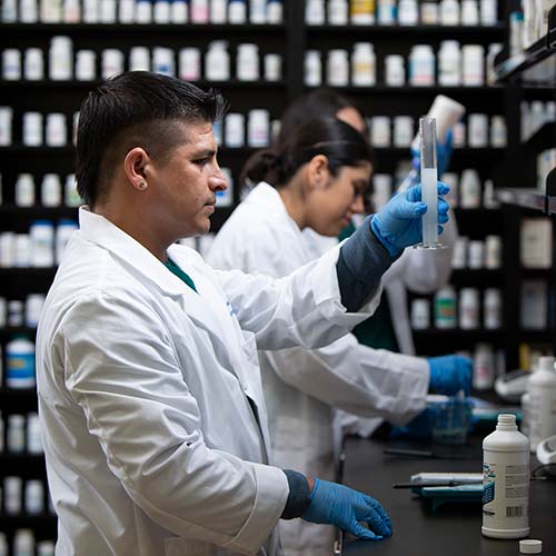 male pharmacy tech measuring out medicine