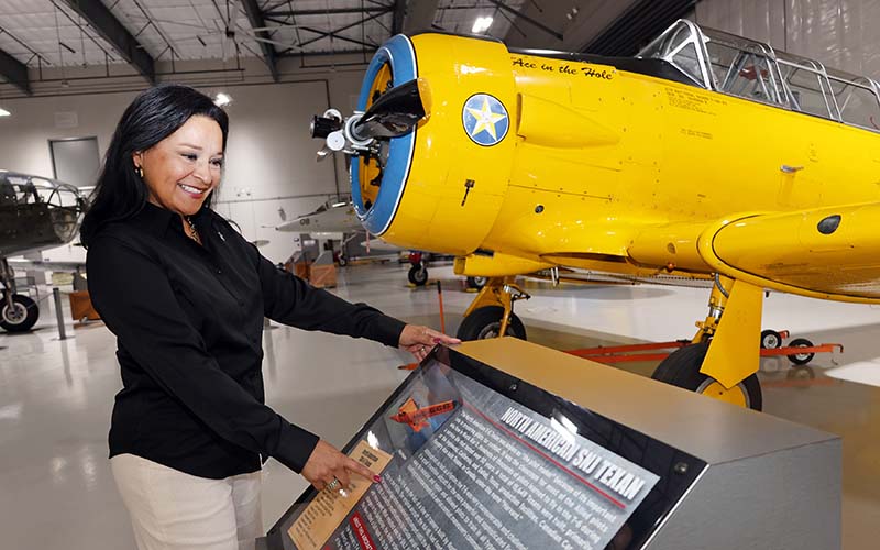 Lone Star Flight Museum president and CEO Anna Hawley standing next to exhibit