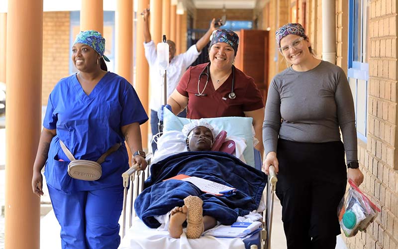 San Jacinto College nursing graduates rolling a Ugandan patient on a gurney