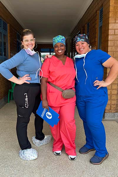 Three nurses posing together outside a rural hospital in Uganda